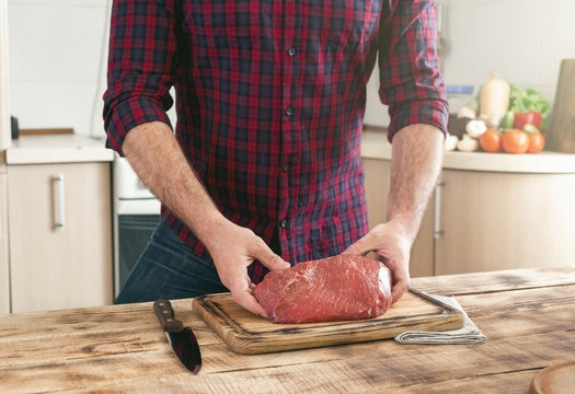 Man holding of fresh piece of beef on wooden table