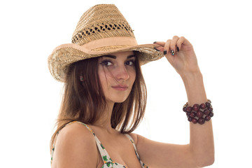 sweet young brunette girl in summer clothes with floral pattern and straw hat looking at the camera isolated on white background