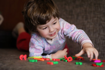 child playing with small toys on the couch in room