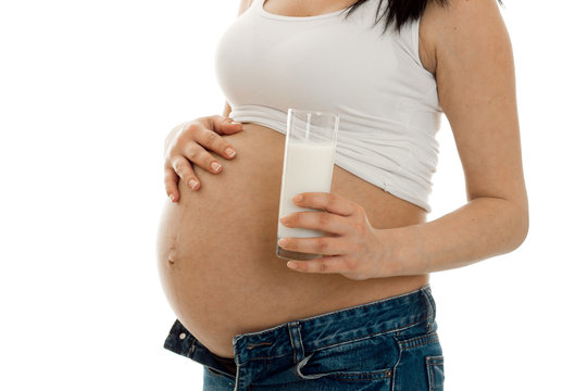 studio portrait of pregnant woman with glasses of milk in her hands isolated on white background