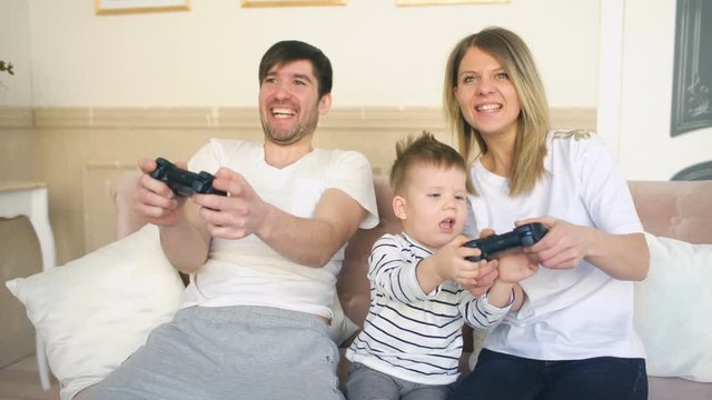 Father and mother of happy family play video game with their son taking gamepad at home