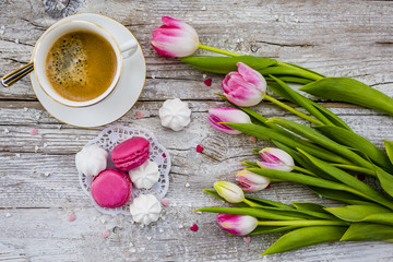 French macaroons delicious cookies with coffee and pink tulips.