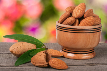 almonds in a bowl on the old wooden board with blurred garden background