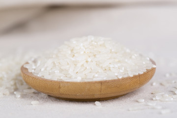 Rice grains closeup in a wooden bowl on a white background.