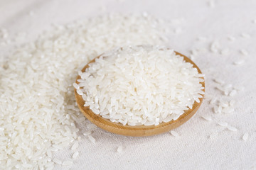 Rice grains closeup in a wooden bowl on a white background.