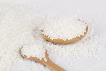 Rice grains closeup in a wooden spoon on a white background.