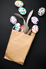 Easter bunny in a paper bag. Rabbit. Black background. Easter ideas. Easter eggs. Space for text.