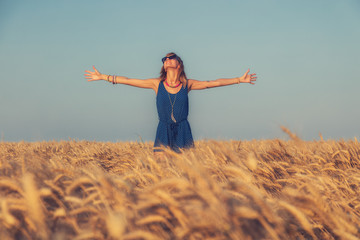 Girl enjoying in a wheat-field with arms wide open.