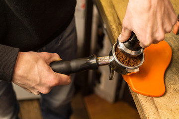 Barista presses ground coffee using tamper.
