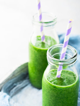 Healthy food concept green smoothie breakfast on white gray tray blue textile. Fruit vegetable juice glass bottle