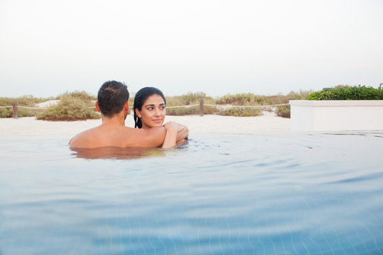 Expat couple embracing in swimming pool.
