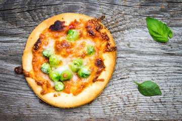 Top View Small Pizza with Peas and Basil Leaves on Wooden Background