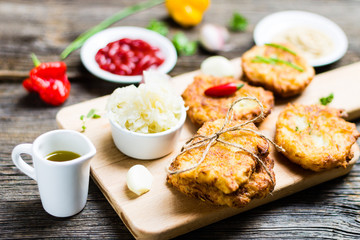 Potato Pancakes on Breadboard with Ingredients on Wooden Background