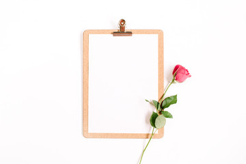 Clipboard mock up and pink rose flower pattern on white background. Flat lay, top view. Flower background.