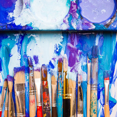 Paints, brushes and palette on the white background. The workplace of the artist. Banner for school