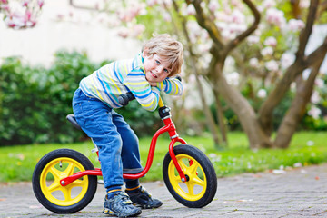 Adorable little kid boy driving his first bike or laufrad