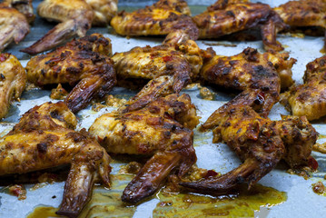 Hot and gold chicken wings with spicy sauce on oven tray