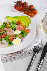 Delicious appetizing vegetable salad with seafood on a white plate. Close-up