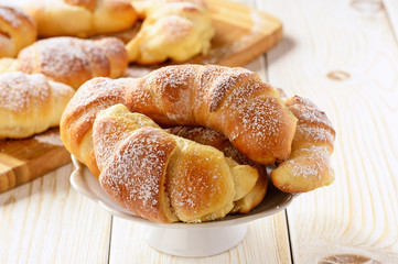 Homemade sweet croissants stuffed with cheese on white table.