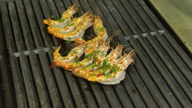 closeup large shrimp fry on the grill sprinkle with spices blows smoke in slow motion