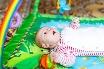 Cute adorable newborn baby playing on colorful toy gym