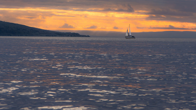 Sunset behind Brean Down in the Bristol Channel, with yacht. Spectacular sky and clouds seen from Weston-super-Mare in Somerset, UK, with fort on peninsula