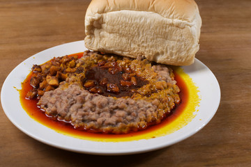 A plate of mashed beans, red palm oil stew and bread