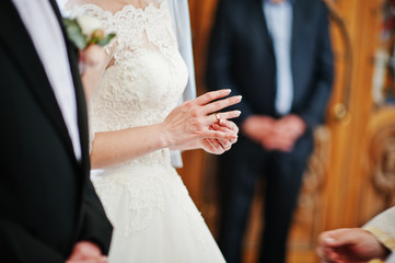 Bride puts wedding ring at hand on church.