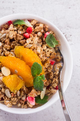 Healthy breakfast - plate of granola with orange slices, mint and seeds close up