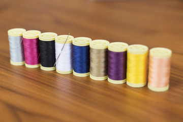 Spools of colorful silk thread on wooden background