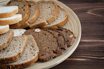 Different types of bread on a plate on a wooden table surface, t