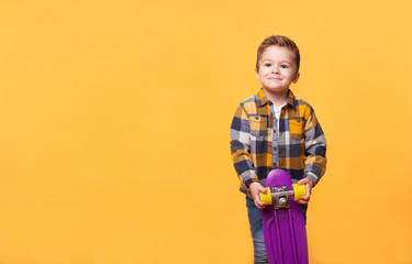 smiling little boy standing with skateboard