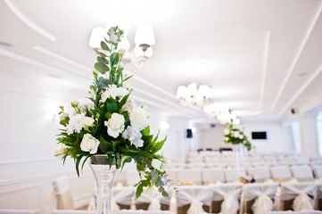 Bouguet of flowers on vase at guest table on wedding hall.