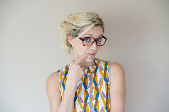 Portrait of blond woman with eyeglasses on beige background