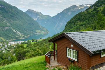 Fototapeta na wymiar Beautiful view at fiord in a summer day with wooden cabin at foreground, Norway