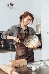 Happy lady standing in kitchen and cooking