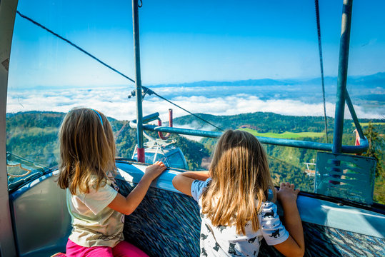 Twin girls riding cabin cable car and enjoying the view.