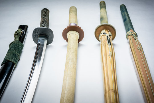 A collection of weapons for training, equipment for Japanese sport Iaido and Kendo. Wood, bamboo and steel sword arranged and displayed. Perspective with selective focus.