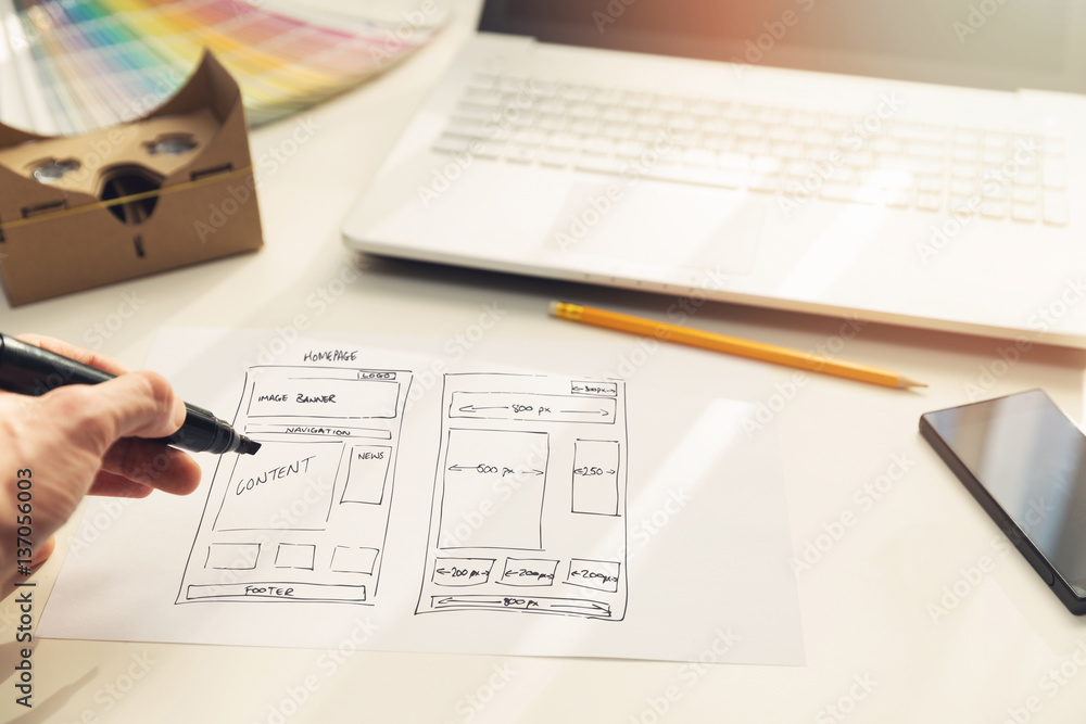 Sticker designer drawing website development wireframe on paper in office