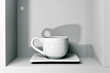 one white Cup and saucer on the shelf