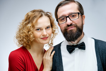Portrait of young couple in love posing at studio dressed in classic clothes