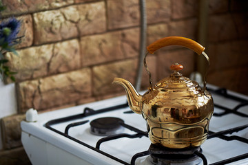Copper kettle stands on an old vintage plate. Kitchen