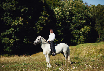 The seriously groom riding a horse