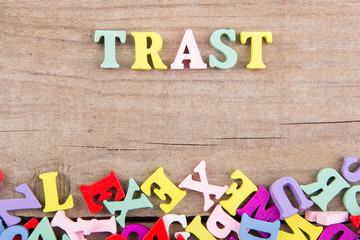 Text "Trast" of colored wooden letters on a wooden background