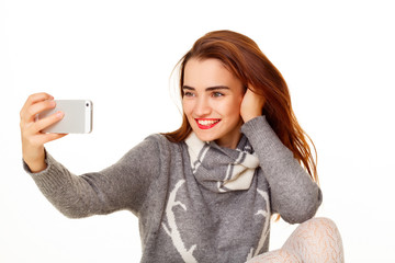 Fototapeta premium Portrait of young beautiful smiley woman making selfie over whit