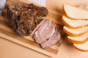 Baked pork with herbs and spice on wooden board and and slices w