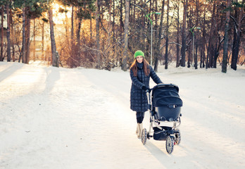 woman with stroller going for a walk in a park during lovely win