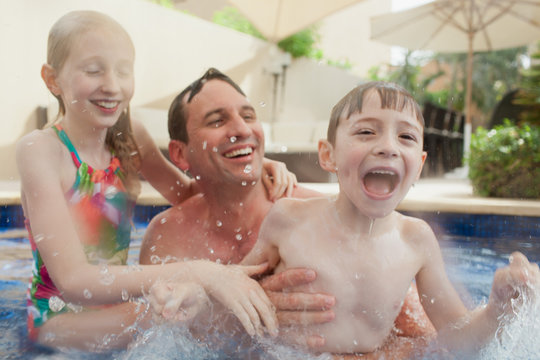 Father with children having fun in swimming pool.