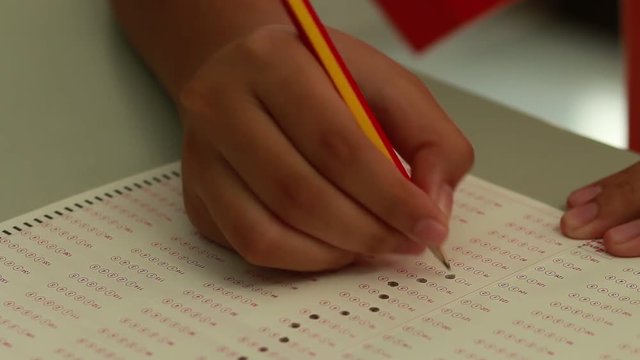 Student test and filling out answer sheets with pencil in classroom at college