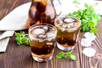 Ice tea with berry and fresh mint in glasses Wooden background